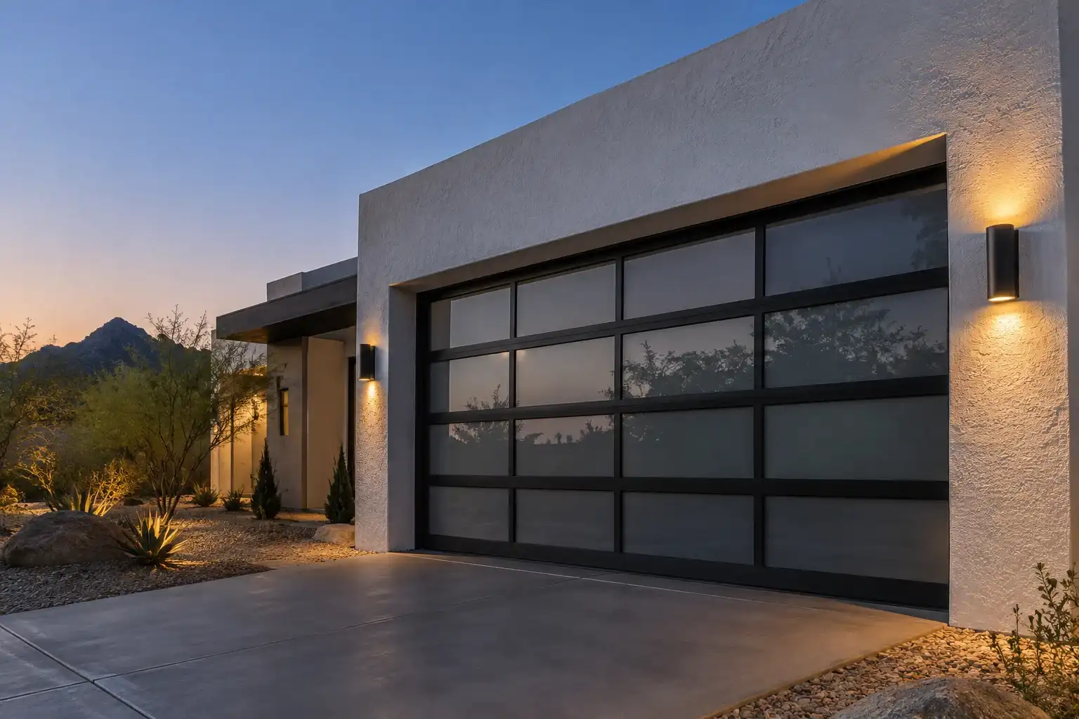 Modern home at dusk with a black frame frosted glass garage door and wall lights